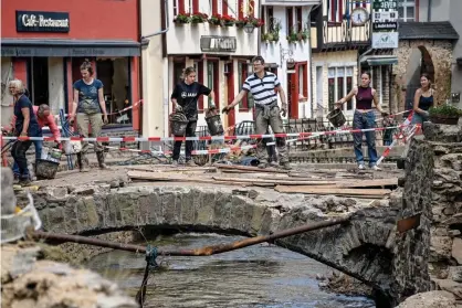  ??  ?? Residents clear debris after heavy rains caused flooding along the river Erft in the village of Bad Muensterei­fel. Photograph: Sascha Steinbach/EPA