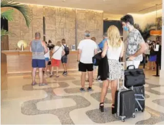  ?? J.C. SOLER ?? Turistas hacen cola en la recepción de un hotel