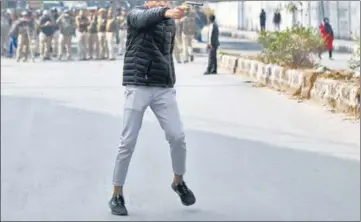 ?? REUTERS ?? The shooter points a gun at protesters outside Jamia Millia Islamia on Thursday. His face has been obscured as he could be a minor.