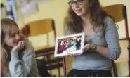  ?? ASSOCIATED PRESS FILE PHOTO ?? Jewish teenager Sophie Steiert, right, shows a picture of Jewish daily life on a tablet as Laura Schulmann looks on during a lesson as part of a religions project July 25 at the Bohnstedt Gymnasium high school in Luckau, Germany.