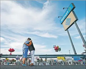  ?? Larry W. Smith EPA-EFE / Rex ?? MOURNERS embrace at a memorial in El Paso. A corrido honoring the dead was performed at shooting site.