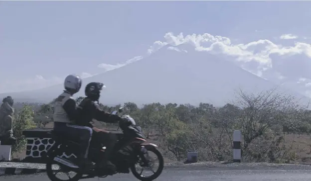  ?? PICTURE; AP ?? A motorbike passenger takes a look at Mount Agung which has been at its highest level of eruption risk since last Friday