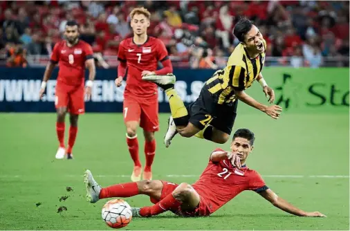  ?? — AP ?? Full-blooded: Malaysia’s Nazirul Naim goes airborne from a challenge by Singapore’s Safuwan Baharudin during a friendly at the Singapore National Stadium yesterday. The match ended goalless.