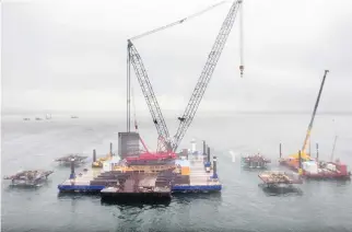  ?? PIERRE OBENDRAUF ?? Cranes on barges on the St. Lawrence River work on footings for the new Champlain Bridge on Thursday. The bridge’s pillars, which are being placed on the footings, are made up of 356 concrete blocks, all with a slightly different shape, that fit...