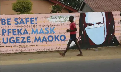  ??  ?? A young boy walks past a wall with graffiti urging people to wear face masks in Harare, Zimbabwe. Photograph: Tsvangiray­i Mukwazhi/ AP