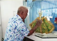  ??  ?? ED TOMBO, a devotee of the Sto. Niño, wipes a handkerchi­ef to take home with him