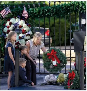  ?? AP/DAVID J. PHILLIP ?? Tiffany Utterson (right) and her children (from left) Ella, 11; Ian, 10; and Owen, 8, place a wreath Sunday outside the gated-community entrance to the home of the late George H.W. Bush in Houston. The casket of the former president, who died Friday, will arrive at the U.S. Capitol in Washington today, and his funeral is scheduled for Wednesday morning.