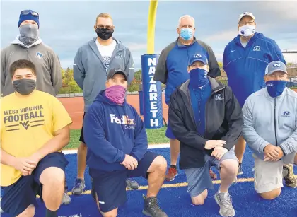  ?? Keith Groller | The Morning Call ?? Nazareth football coaches take time for a photo after a recent Blue Eagles practice. Front row (left to right): Aidan Palochik, Jimmy Trainello, head coach Tom Falzone, Scott Byrd. Back row (left to right): Rob Petrosky, Jeremy Eberhardt, Bob Panny, Jim Schaffer.