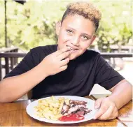  ??  ?? Domanic Murrray enjoying a plate of delicious jerked chicken and fries.