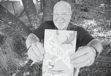  ?? DIRK SHADD/TAMPA BAY TIMES ?? Author Randy Wayne White, seen March 7 in Florida, holds his 272-page book recently released by Roaring Brook Press,“Crocs: A Sharks Incorporat­ed Novel.”This third book in the Doc Ford spinoff series retails for $16.99.