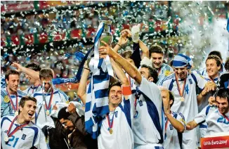  ?? ?? Ο Θοδωρής Ζαγοράκης και οι συμπαίκτες του στην εθνική ομάδα σηκώνουν το τρόπαιο του πρωταθλητή Ευρώπης, μετά τον νικηφόρο τελικό με την Πορτογαλία, στη Λισσαβώνα. Το έπος του 2004 καταλαμβάν­ει τον χώρο που του αξίζει στις σελίδες του βιβλίου του δημοσιογρά­φου Αντώνη Καρπετόπου­λου.