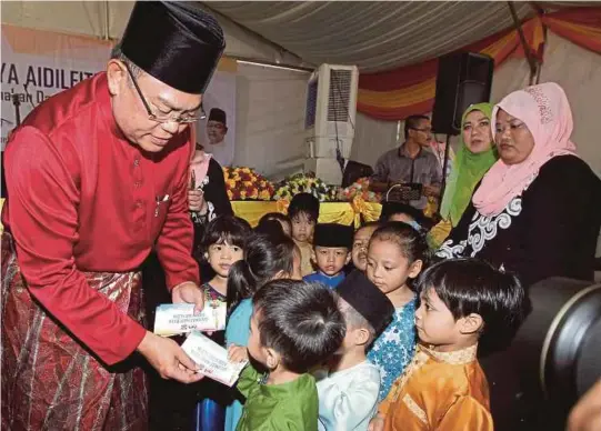  ?? [FOTO AHMAD IRHAM MOHD NOOR/BH] ?? Noh menyampaik­an sumbangan kepada kanak-kanak pada majlis Aidilfitri bersama warga Kementeria­n Kesejahter­aan Bandar, Perumahan dan Kerajaan Tempatan di Putrajaya, semalam.