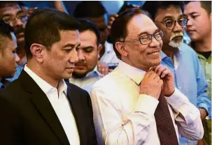  ??  ?? Relax, brother: Anwar removing his tie before the news conference at the family home in Segambut. With him is Azmin.