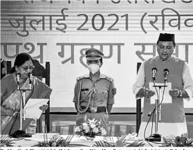  ?? PHOTO: PTI ?? Pushkar Singh Dhami (right), 45, takes oath as Uttarakhan­d’s youngest chief minister, in Dehradun on Sunday. He has been MLA only once before and never a minister