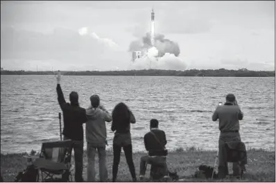  ?? AP/Houston Chronicle/SMILEY N. POOL ?? Spectators at Cape Canaveral, Fla., cheer as a rocket lifts off, carrying NASA’s Orion capsule aloft Friday.