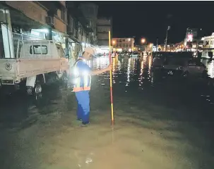  ??  ?? BANJIR KILAT: Anggota APM Sri Aman menyukat ketinggian air akibat banjir kilat di Sri Aman malam kelmarin.