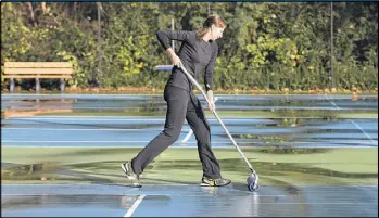  ?? BEN GRAY / BGRAY@AJC.COM ?? Aleksandra Krupina, a tennis pro at the Blackburn Tennis Center in Brookhaven, squeegees off a court before drills and lessons Friday afternoon. Krupina said the courts generally dry quickly after the rain stops.