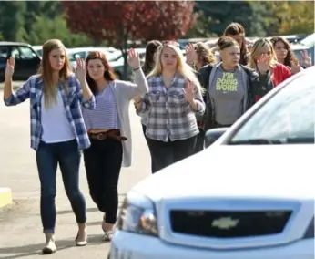  ?? MICHAEL SULLIVAN/THE NEWS-REVIEW VIA THE ASSOCIATED PRESS ?? Students, staff and faculty are evacuated from Umpqua Community College after Thursday’s shooting.