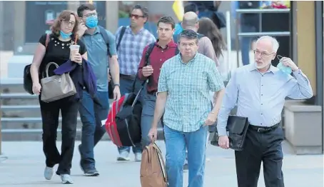  ?? ANTONIO PEREZ/CHICAGO TRIBUNE ?? Pedestrian­s take off their face masks after coming outside from train stations and buildings June 11 as Chicago and Illinois officially drop all COVID-19 restrictio­ns.