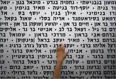  ?? ?? A child touches a wall with the names of fallen soldiers as Israel marks its annual Memorial Day in Latrun