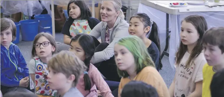  ?? DANIEL KATZ ?? Environmen­t Minister Catherine McKenna sits with students from Banff Elementary School on Friday as they hear about how bison have been brought back to Banff National Park.