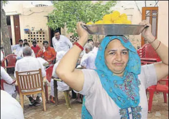  ?? MANOJ DHAKA/HT ?? Boxer Amit Panghal's mother Usha Rani carries ‘laddoos’ for relatives and villagers gathered at their house at Mayna village in Rohtak district on Saturday.