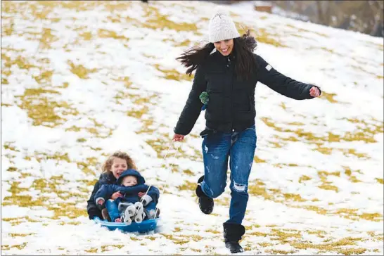  ?? WADE VANDERVORT ?? A rare snowfall means a play day for this trio Tuesday at Fox Hill Park in Summerlin.