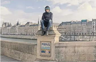  ?? ANDREA MANTOVANI FOR THE NEW YORK TIMES ?? Invader, known for his Parisian street mosaics, posing in a mask with one of his works along the Seine.