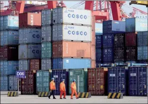  ?? AP ?? Workers pass shipping containers Wednesday at a port in Qingdao in eastern China’s Shandong province. China’s exports fell 1.4 percent in December, compared with a year ago, to $224.1 billion.