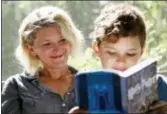  ??  ?? Theo Galkin, 8, rereads a favorite part of “Harry Potter and the Sorcerer’s Stone” while posing for a picture with his mother Chloe Galkin at their home in South Orange, N.J., Wednesday