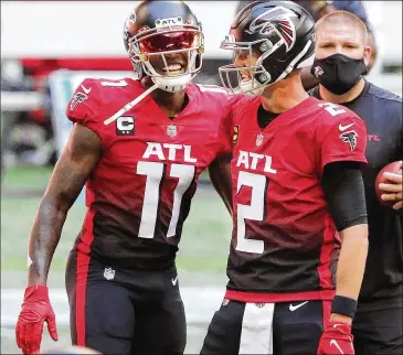  ?? CURTIS COMPTON/ CURTIS. COMPTON@ AJC. COM ?? Falcons quarterbac­k Matt Ryan and wide receiver Julio Jones share a hug as they prepare to play the Lions on Oct. 25 in Atlanta. Both stars would count heavily toward the salary cap in 2021.