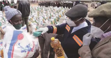  ?? — ?? Vice President Constantin­o Chiwenga hands over groceries to Mrs Monica Khupe, while Finance and Economic Developmen­t Minister Professor Mthuli Ncube looks on at Bulawayo Kraal Irrigation Scheme in Binga yesterday. Picture: Eliah Saushoma.