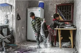  ?? Aaref Watad / AFP/Getty Images ?? Syrian boys clean up trays and utensils after a house was damaged by a reported airstrike in the rebel-held town of Orum al-Kubra in the northern Syrian province of Aleppo on Saturday. The U.S. has 2,000 troops in Syria, most of them in the northeaste­rn part of the nation.