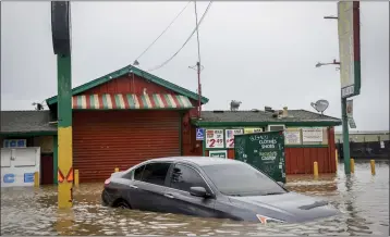  ?? BRONTË WITTPENN — SAN FRANCISCO CHRONICLE VIA AP ?? Floodwater from a breached levee submerges cars and floods businesses on Salinas Road in Pajaro on Tuesday.