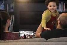  ?? aP ?? PRAYING AT HOME: Ahmad Kamel lifts his son Yusuf, 2, as his wife Nadia Chaouch sits next to them in their Seattle home recently as the family watches a livestream of the previous day’s Taraweeh prayer from the nearly empty Muslim Associatio­n of Puget Sound mosque.