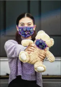  ?? KASSI JACKSON / HARTFORD COURANT ?? Olivia Carlson and her teddy bear wear matching purple masks at her home last month in Connecticu­t. Carlson, a college senior and dance teacher, recently began selling teddy bears with masks and matching ones for children as a source of entertainm­ent and comfort for kids during quarantine.