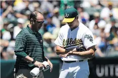  ?? JASON O. WATSON/GETTY IMAGES ?? Nick Paparesta examines Oakland’s Rich Hill, who was removed from the game after five pitches Sunday.