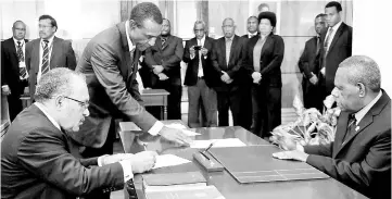  ??  ?? Photo shows O’Neill (left) signing his oath of office before Governor-General Bob Dadae (right) in Port Moresby. — AFP photo