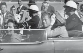  ?? JIM ALTGENS — THE ASSOCIATED PRESS FILE ?? In this file photo, President John F. Kennedy waves from his car in a motorcade in Dallas. Riding with Kennedy are First Lady Jacqueline Kennedy, right, Nellie