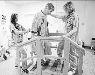  ?? CHRIS YOUNG THE CANADIAN PRESS ?? Physiother­apist Ellen Newbold, right, and occupation­al therapist Mary Van Impe help Tim Heenan walk up some steps as he prepares for his release following day surgery for a hip replacemen­t at St. Michael's Hospital in Toronto.