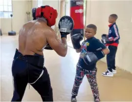  ?? ANGELE LATHAM/THE JACKSON SUN VIA AP ?? Jackson Boxing Club member Kaecilius Qadir, left, teaches a young participan­t how to throw a punch on May 23 at Jackson Boxing Club in Jackson, Tenn.