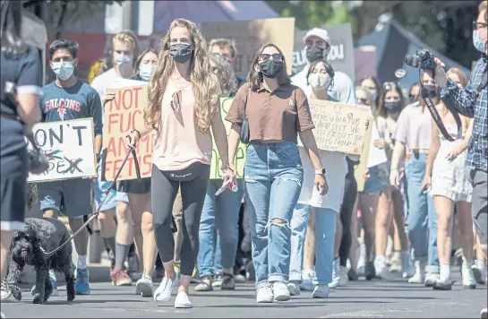  ?? PHOTOS BY ANDA CHU — STAFF PHOTOGRAPH­ER ?? Heather Hennessy, center, leads a march along North Santa Cruz Avenue along with a group of over a hundred people organized by Los Gatos High School students in a show of solidarity with sex abuse and sexual assault survivors in Los Gatos on Tuesday.