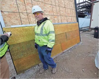  ?? MIKE DE SISTI / MILWAUKEE JOURNAL SENTINEL ?? Denver Callahan, senior superinten­dent for Mortenson Constructi­on, stands near the bronze-colored zinc panels that will cover the outside of the new Milwaukee Bucks arena. More photos at jsonline.com/business.