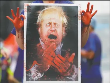  ?? (File Photo/AP/Kirsty Wiggleswor­th) ?? A nurse holds a painting of Prime Minister Boris Johnson clapping with blood on his hands in August as part of a demonstrat­ion of National Health Service workers at hospitals across London to demand a 15% pay raise from the government in London.