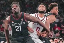  ?? BEBETO MATTHEWS/AP PHOTO ?? UConn forward Adama Sanogo, left, and guard Nahiem Alleyne, right, sandwich St. John’s guard Posh Alexander, center, on a rebound during the second half of a game on Feb. 25 in New York.