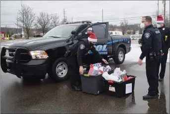  ?? PHOTOS BY NATALIE BRODA — THE OAKLAND PRESS ?? Auburn Hills police officers unload gifts for two of 13 local families adopted by the department this holiday season.