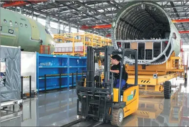  ?? TIAN HE / FOR CHINA DAILY ?? An employee drives a forklift at an assembly line for Airbus A320 aircraft in Tianjin.