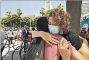  ?? Al Seib Los Angeles Times ?? SUNFLOWER HAZE, right, hugs Mike L. after a news conference outside the LAPD headquarte­rs.