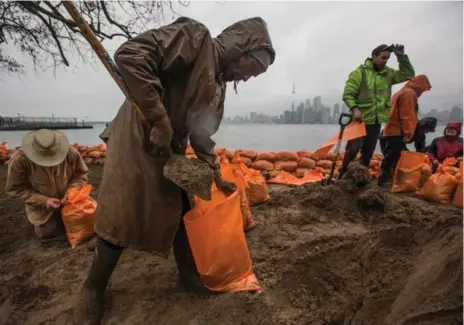  ?? JESSE WINTER PHOTOS/TORONTO STAR ?? Wards Island residents and city workers fill sandbags in preparatio­n for rising water levels and potential flooding as heavy rains are predicted to hit.