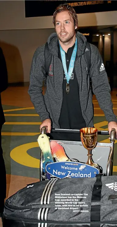  ??  ?? New Zealand co-captain Tim Mikkelson has the Melrose Cup, awarded to the winning World Cup men’s team, with him as he arrives at Auckland Airport.
